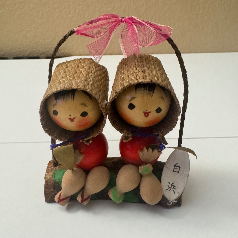 Vintage Japanese Kokeshi seated on rustic log,wearing traditional sandals 1970's